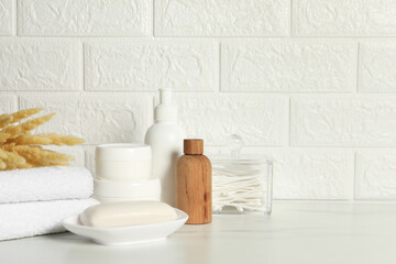 Different bath accessories, personal care products and spikelets on white table near brick wall, space for text