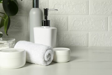 Different bath accessories and personal care products on white table near brick wall, space for text