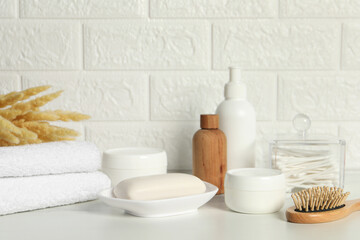 Different bath accessories, personal care products and spikelets on white table near brick wall