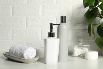 Fototapeta na wymiar Different bath accessories and personal care products on white table near brick wall