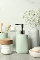 Different bath accessories, personal care products and gypsophila flowers in vase on gray table...