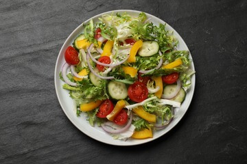 Tasty fresh vegetarian salad on black table, top view