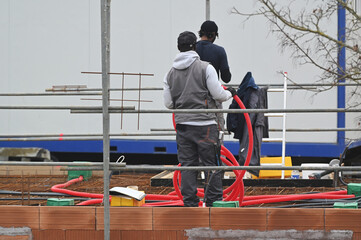 ouvriers électricien posant des ourreaux plastiques sur un plancher de pavillon - 752152016