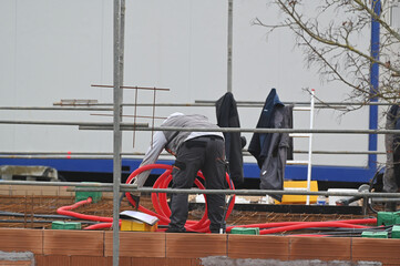 ouvriers électricien posant des ourreaux plastiques sur un plancher de pavillon - 752152019