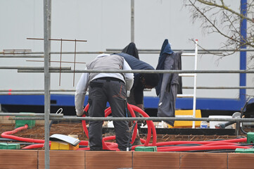 ouvriers électricien posant des ourreaux plastiques sur un plancher de pavillon - 752152047