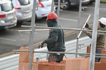 ouvrier maçon posant des briques sur un chantier de construction - 752152071