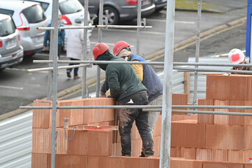 ouvrier maçon posant des briques sur un chantier de construction - 752152091