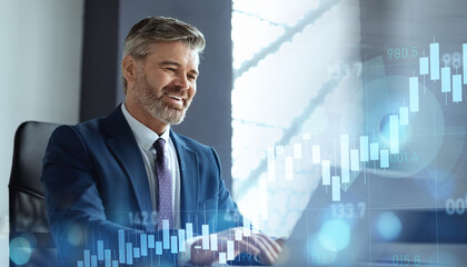 A confident senior businessman smiles while working on a laptop, with transparent digital financial charts