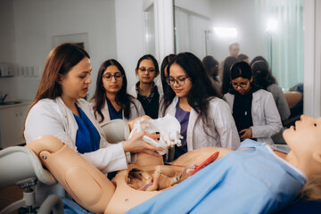 Students of obstetrics and gynecology reproduce the reality of childbirth on a special mannequin. - obrazy, fototapety, plakaty