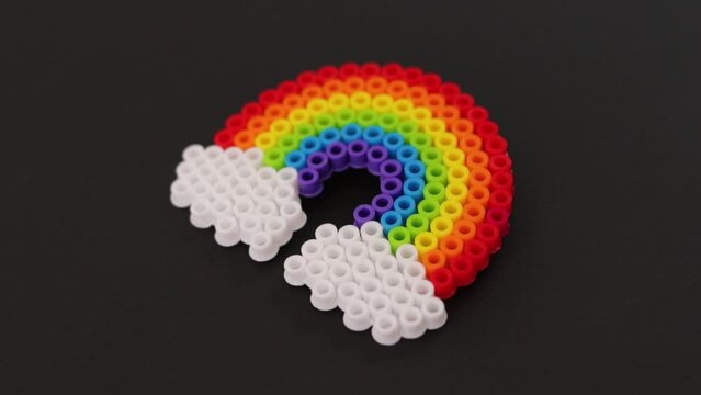 Colorful plastic bead rainbow on black background, vibrant craft project