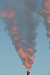 industrial chimneys with heavy smoke causing air pollution as ecological problem on pink sunset sky background 