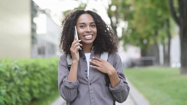 Young beautiful woman using smartphone in a city. Smiling student girl talking on mobile phone outdoor. Modern lifestyle, connection, casual business concept
