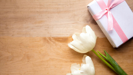 Obraz na płótnie Canvas White tulips and gift box on wooden background, copy space for the text