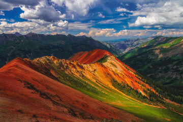 Mountains glow at sunset in Colorado, under fluffy clouds