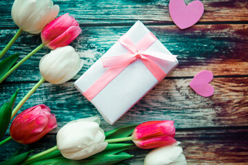 bouquet of pink and white tulips and gift box on wooden background. Easter or Mother's Day greeting card. Copy space for the text