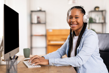 Happy black student lady in headphones engaging in online studies