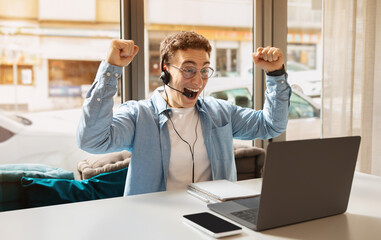 Exuberant young man with curly hair, wearing a headset and a blue shirt