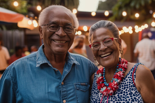 Mixed raced elderly couple smiling surrounded by party participants.