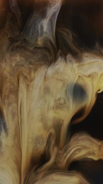 Coffee creamer or milk being poured into a cup of iced coffee.  Closeup vertical video in slow motion.