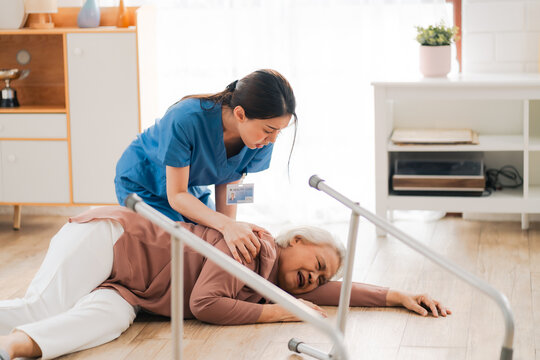 senior patient falling on the ground floor at home, Asian caregiver helping elderly older female from accident after doing physical therapy then rescued by attractive therapist nurse, health insurance
