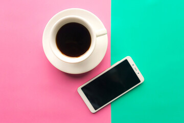 Coffee cup and mockup mobile on green and pink pastel background. Top view. Minimal concept