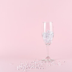 Wine glass full of diamonds on pink background. Creative minimal party concept.