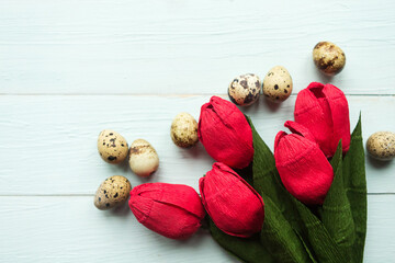 Red tulips and quail eggs on wooden background. Easter concept