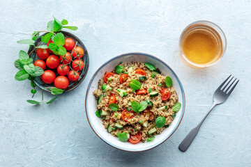 Quinoa tabbouleh salad in a bowl, a healthy dinner with tomatoes and mint, with a drink, overhead shot - 752171450