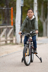Happy smiling kid riding in his bicycle in a park