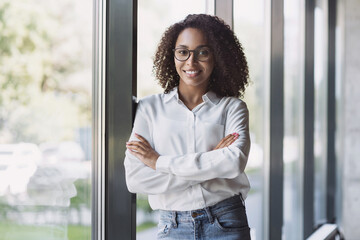Young businesswoman portrait. Self confident young woman with crossed arms smiling at office. People, business casual, self confidence, leadership concepts