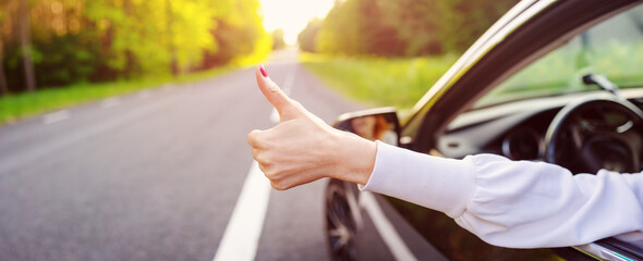 Woman inside her car gesticulate thumb up.