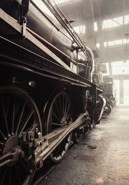 Steam era - old steam locomotive in train shed. Steam locomotive in depot. Image in warm tones (almost sepia). Depot interior space behind filled with mist smoke.