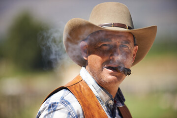 Portrait, cowboy and man smoking cigar at farm in the rural countryside in Texas. Ranch, face and...