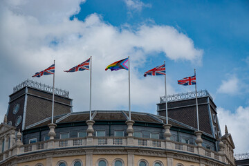 Union Jack and Pride flags flying side by side atop an old government building