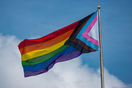 CLOSE UP: Vibrant Pride flag fluttering in the wind with a blue sky backdrop