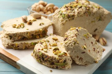 Pieces of tasty halva with pistachios on table, closeup
