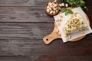 Piece of tasty halva with pistachios and mint on wooden table, flat lay. Space for text