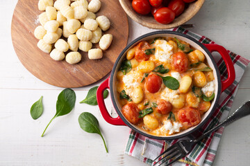 Top view of gnocchi in creamy tomato sauce with spinach and melted mozzarella on a white background