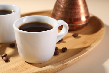Delicious coffee in cups and beans on wooden board, closeup