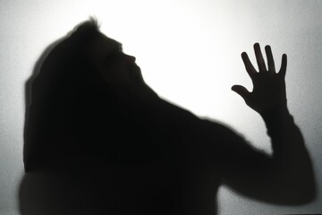 Silhouette of ghost behind glass against light grey background