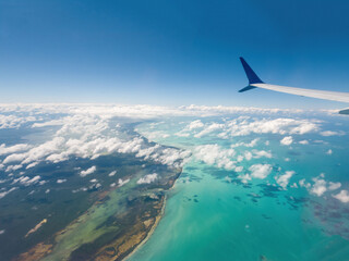 Fototapeta premium Airplane flying above ocean with clouds and sea below