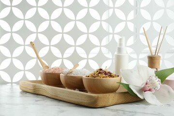 Beautiful composition with different spa products and orchid on white marble table