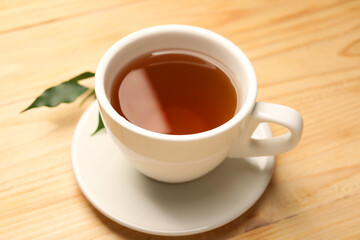 Tasty tea in cup on light wooden table, closeup