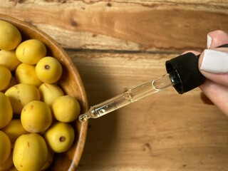 Marula fruit cosmetic oil in a dropper with marula fruit in soft focus