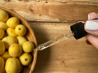 Marula fruit cosmetic oil in a dropper with marula fruit in soft focus
