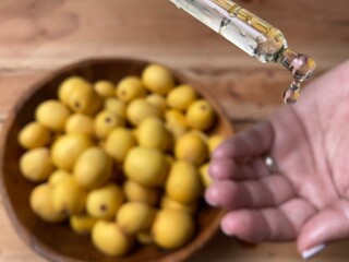 Marula fruit cosmetic oil in a dropper with marula fruit in soft focus