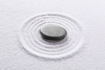 Zen garden stone on white sand with pattern