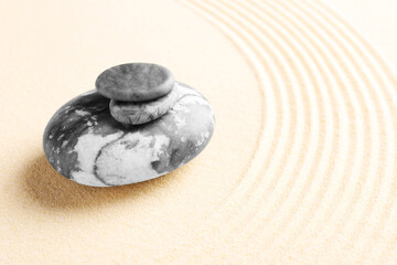 Fototapeta na wymiar Zen garden stones on beige sand with pattern. Space for text