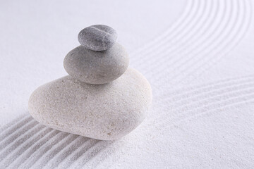 Fototapeta na wymiar Zen garden stones on white sand with pattern, space for text