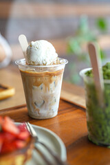 Close up and selective focus glass of iced coffee with milk and ice cream on wooden table.